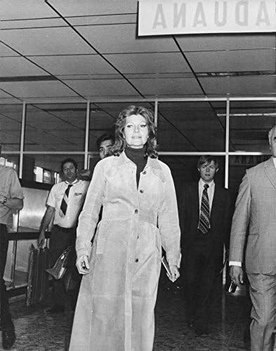 Гроздобер фотографија на Рита Хејворт облечена во палто, излегувајќи од аеродромот.